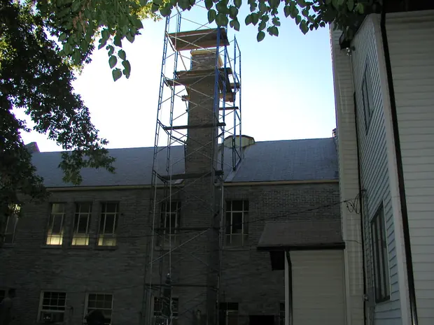 Scaffold tower erected the full height of a church chimney beside a slate roof