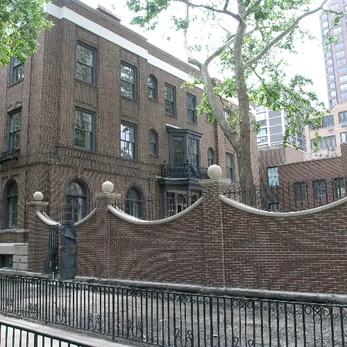 Historic brick mansion on a Gold Coast street behind a decorative brick and iron wall