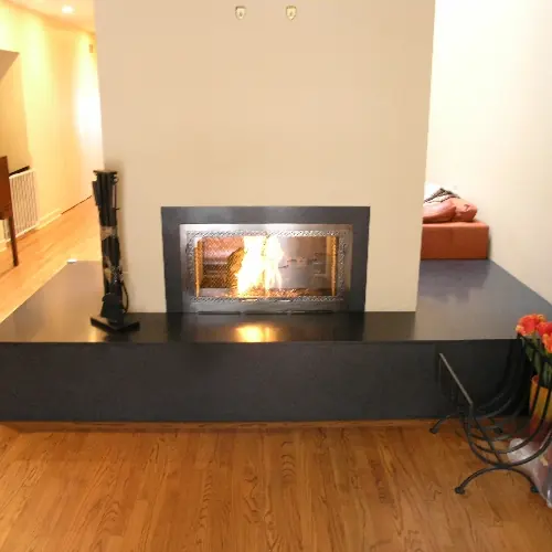 Modern raised-hearth fireplace with a polished steel door frame and fire burning inside